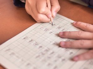 Homepage 59 Child practising Foundation Chinese character writing with a pencil on gridded paper